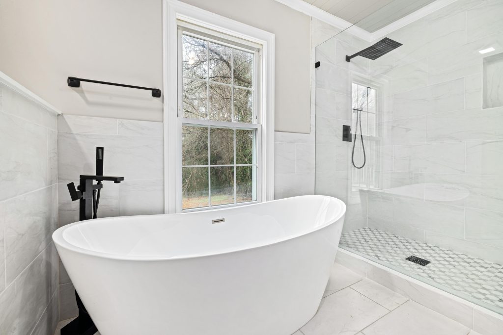 Bright modern bathroom featuring a sleek freestanding bathtub and a glass shower enclosure.