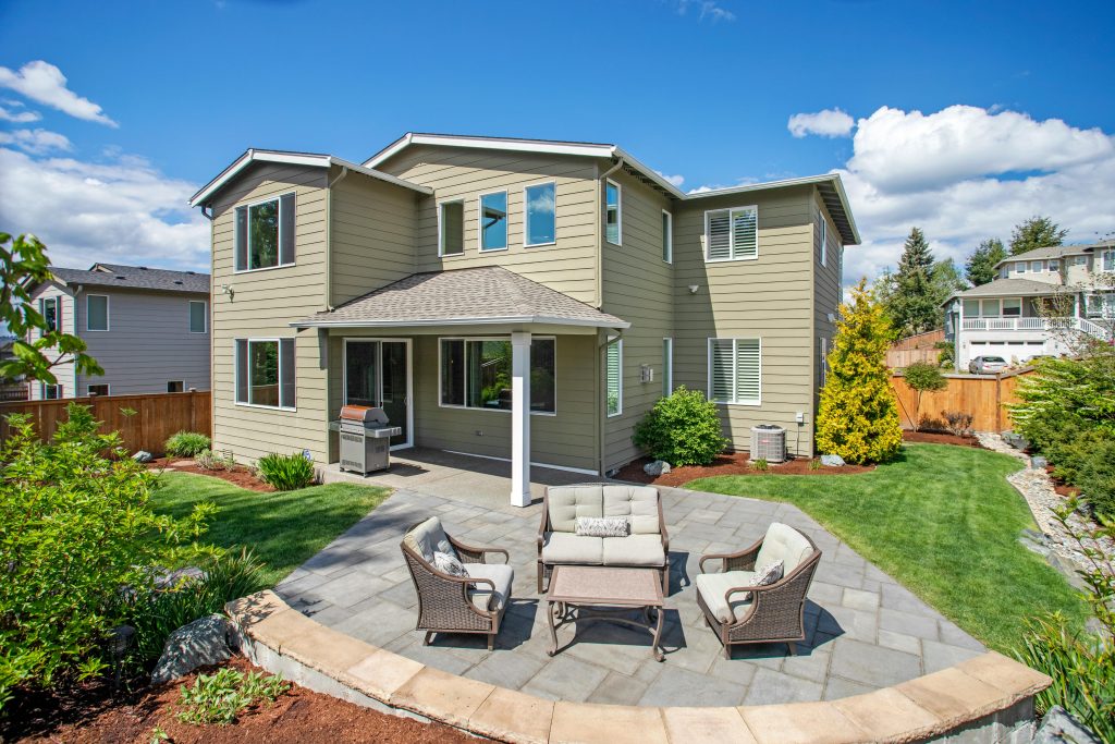 Explore a sunny suburban backyard with patio seating and landscaped garden.