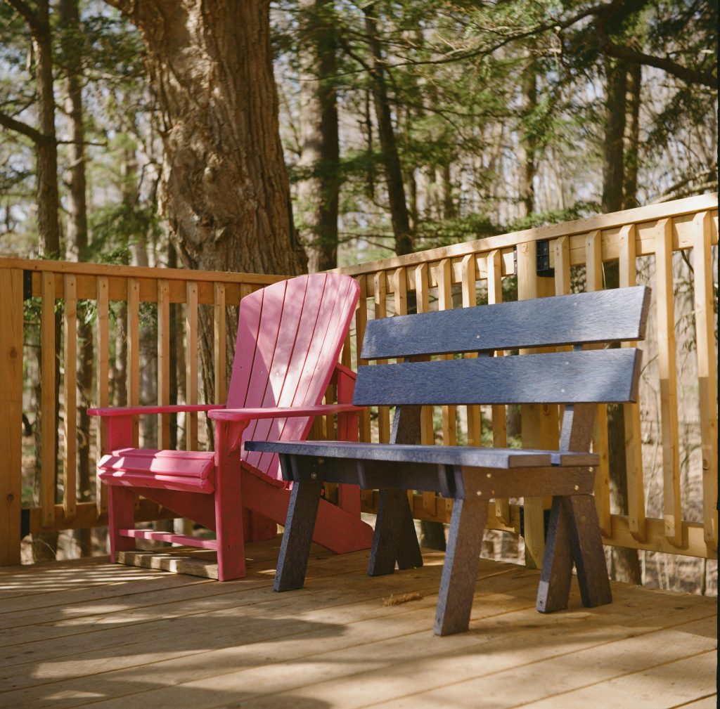 pexels-photo-34343530-34343530 Vibrant outdoor seating on a wooden deck surrounded by forest scenery.