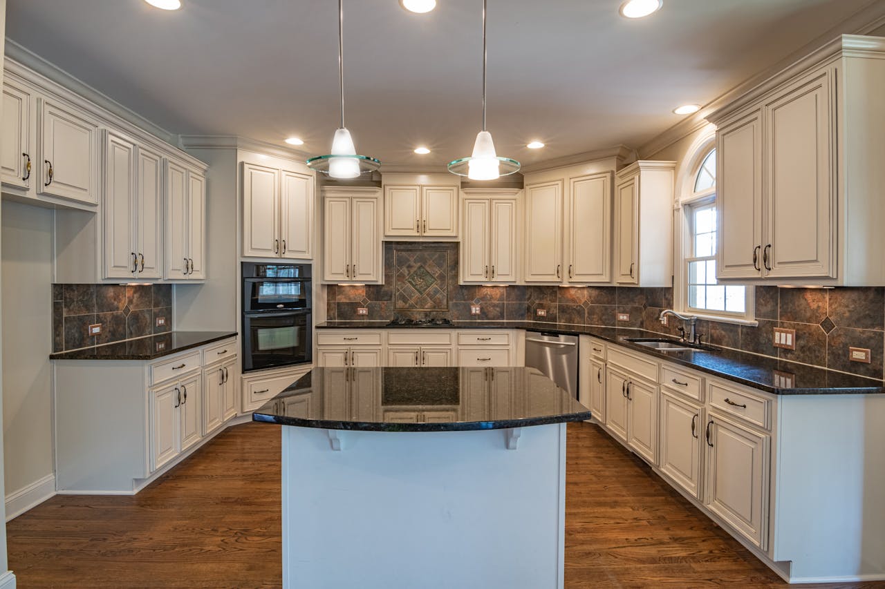 Spacious kitchen featuring elegant white cabinets, granite countertops, and modern lighting.
