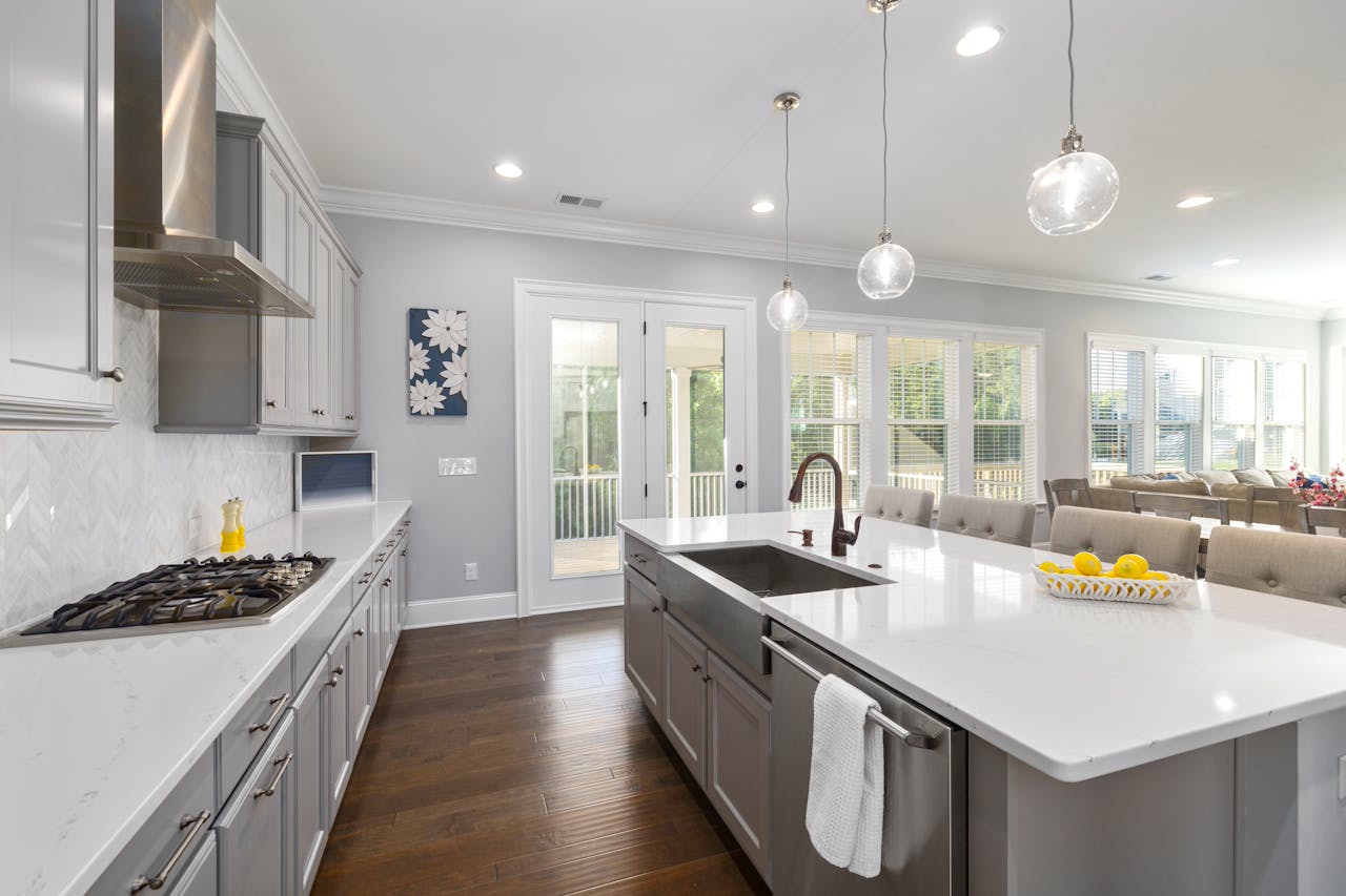 Spacious modern kitchen featuring white countertops, grey cabinets, and natural light.